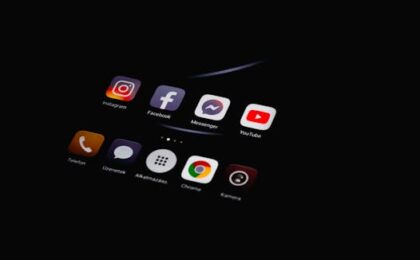 Close-up of smartphone displaying popular social media apps in dim lighting.